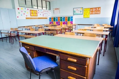 A picture of a classroom with desks, chairs, and posters on the walls.