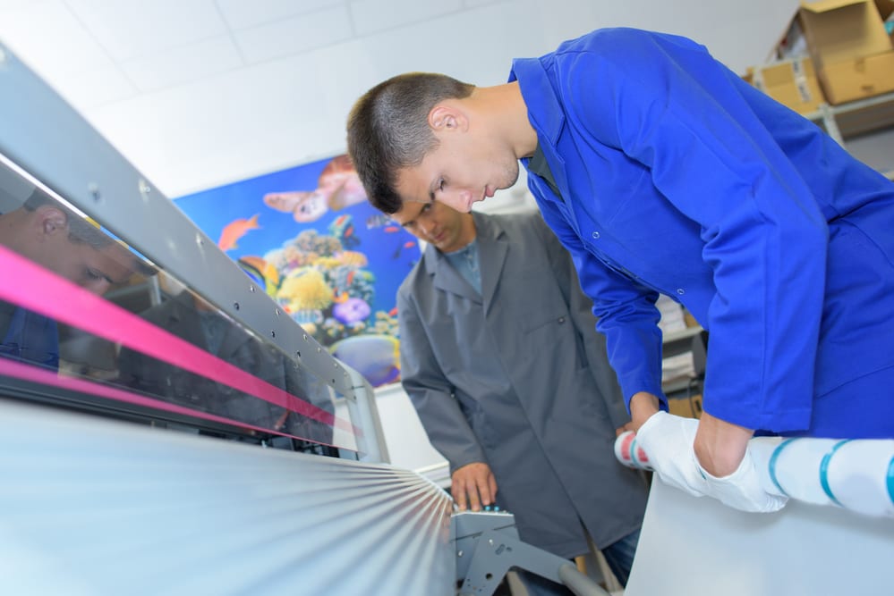 two people looking over a printing machine