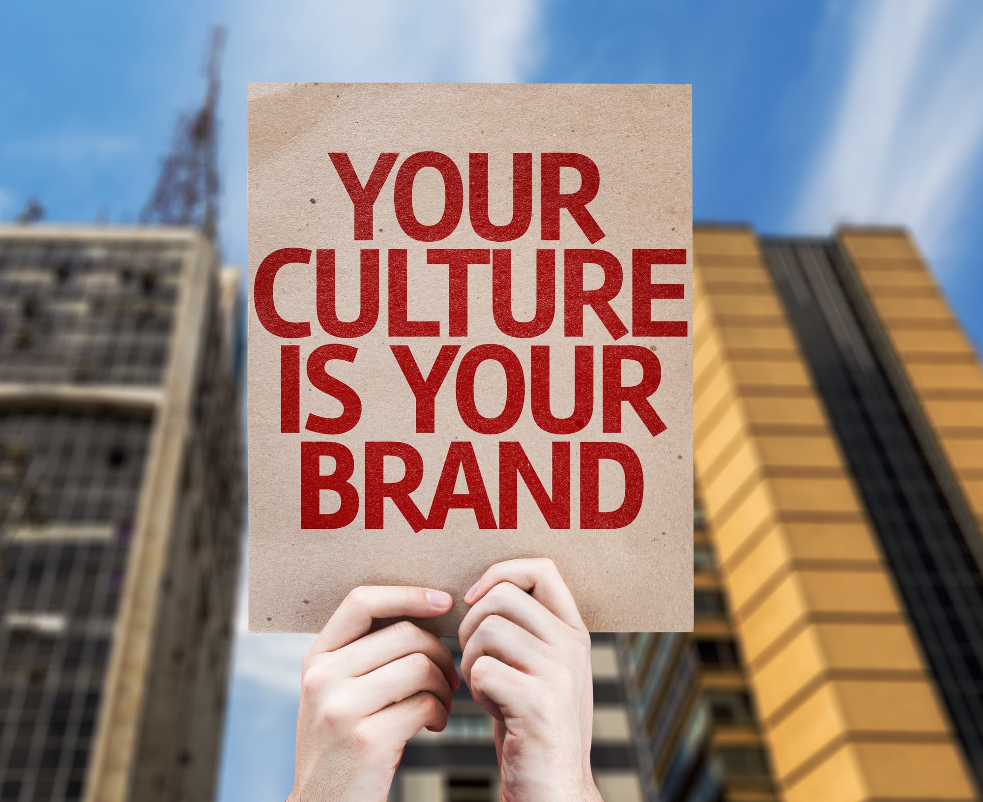 Hands holding up sign that reads: YOUR CULTURE IS YOUR BRAND